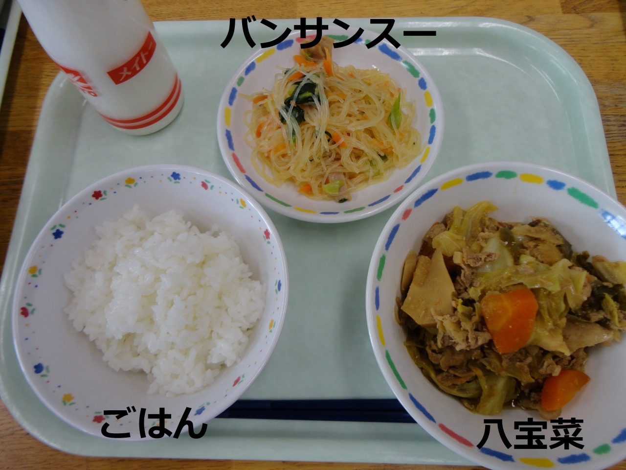 手前にごはんと八宝菜、奥に牛乳とバンサンスーを並べた給食の写真