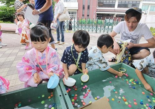 浴衣姿の子どもたちがスーパーボールすくいをしている様子の写真