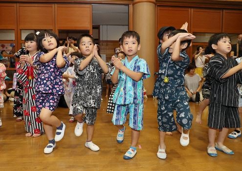浴衣を着た子どもたちがホールで盆踊りをしている様子の写真