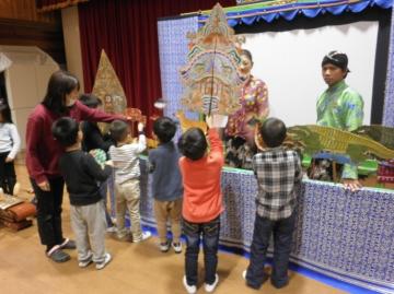 子どもたちが影絵の道具を見せてもらっている様子の写真