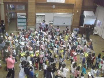 鬼のお面をかぶった園児と、関係者がホールに集まっている写真