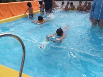 ビート板を使ってプールでバタ足の練習をしている子どもたちの写真