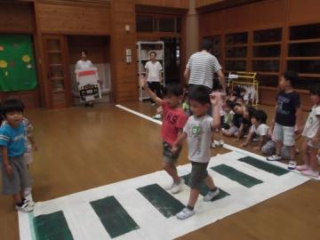 横断歩道が書かれたシートの上を歩き、横断歩道を渡る練習をしている子どもたちの写真
