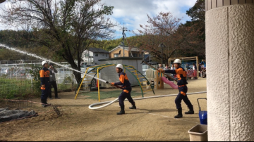 消防団の皆さんが小型ポンプを使った放水訓練をしてる写真