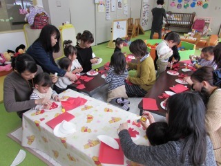 親子たちが机にむかいお面を作っている写真