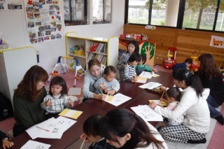 テーブルの前に座っている参加者親子が、絵本を作っている写真