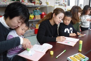 子どもと一緒に糊付けをしたり、色塗りをしたりしながら、子どもの名前の頭文字をとって絵にしている写真