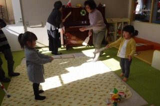 おばあちゃんと子供たちが羽根つきをしている写真