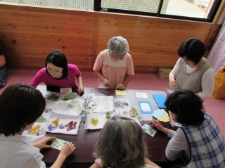 机の上で紙に花をのせて押し花を作っている写真