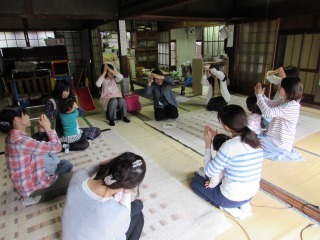 親子が円を描くように輪になって座り、わらべうたを楽しんでいる写真