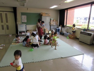 室内のマットの上で保育士が子どもと遊んでいる写真