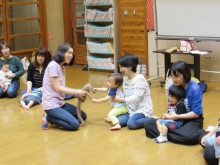 おさるの人形と子どもが握手している写真