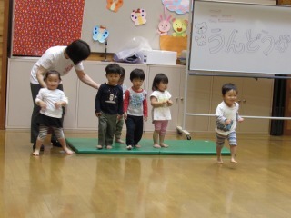 子どもたちが緑のマットの上に横に並んで立っている写真