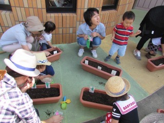 ママと子どもがプランターに種をまいている写真