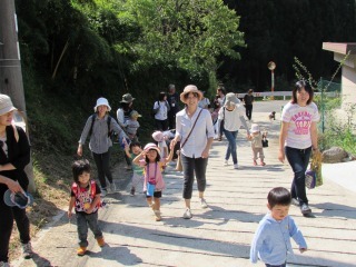 坂道を手をつないだ親子が歩いている写真