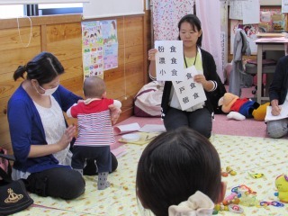 「粉食、濃食、小食、孤食、戸食、個食」の文字が書かれた紙を示し、6つの食について話をしている栄養士と、話を聞いている参加者の写真