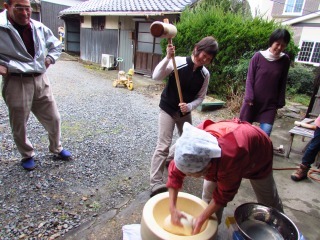 外でお母さんが餅つきをしている写真