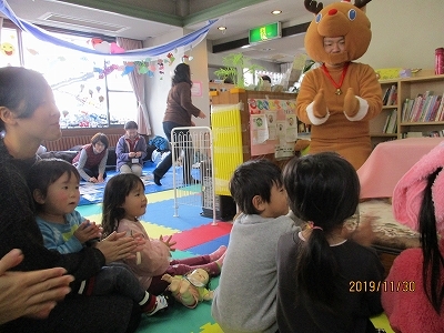 着ぐるみのトナカイさんと手遊びで楽しんでいる様子の写真