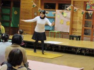 木の板の上で、白いセータの女性がタップダンスを披露している写真