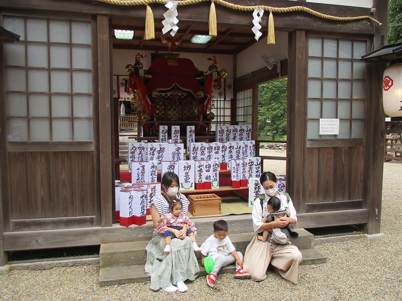 お神輿の前での母親と子ども達の記念写真