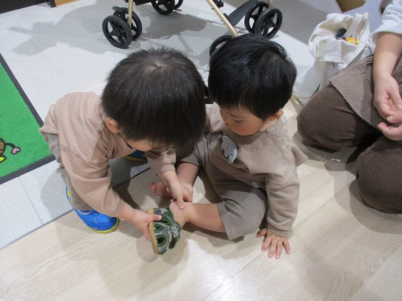 弟に靴を履かせている男の子の写真