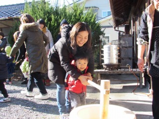 杵を持ってママと一緒にお餅をついている写真