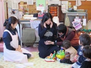 パパがママのお腹に聴診器をあてて赤ちゃんの心音を聞いている写真