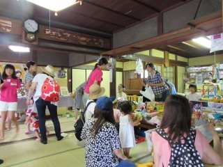 畳の部屋に沢山の品物が置かれ、バザーをしている写真