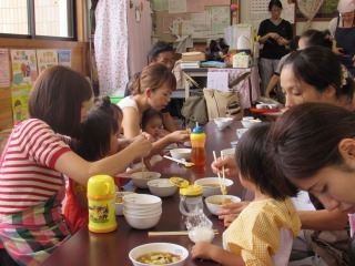 味噌汁とおにぎりを食べている親子の写真