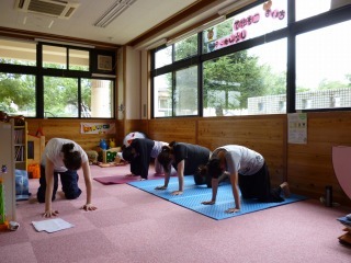 寺西しのぶ先生とママ達が手と膝を床についてヨガのポーズをしている写真