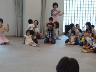 親子が床に座り手遊びをしている写真
