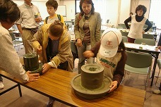 屋内でのお抹茶体験で石臼をひいている参加者たちの写真