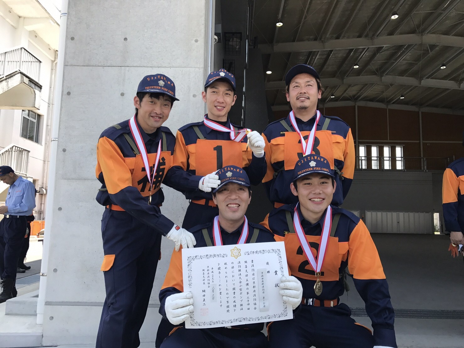 優勝メダルと賞状を持ち優勝を喜ぶ第1分団選抜の選手たちの写真