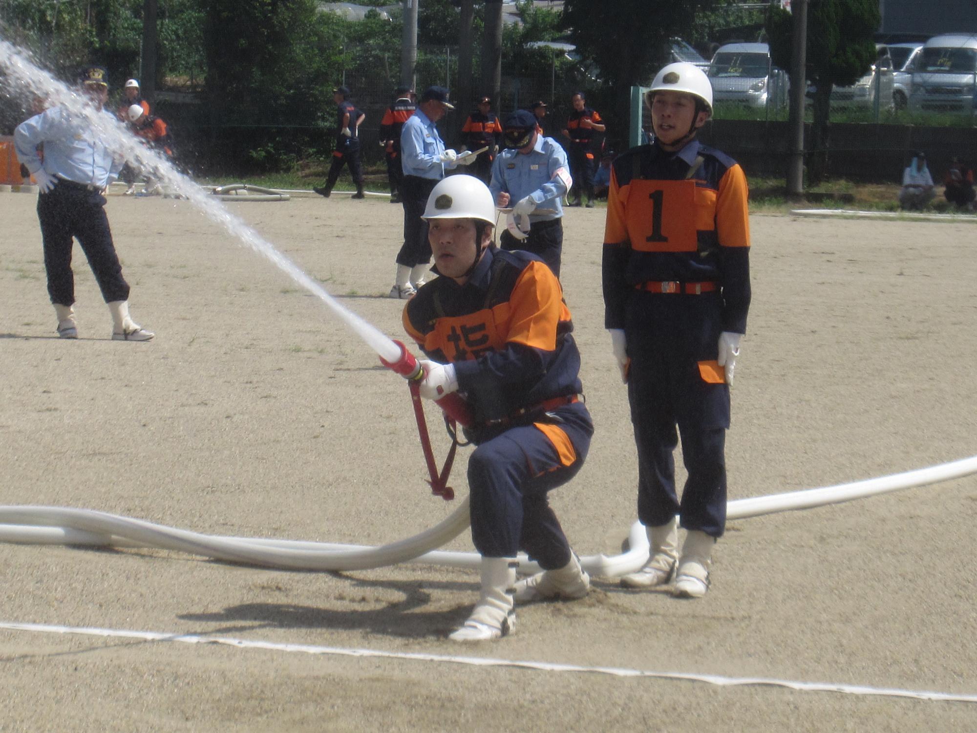 小型ポンプ操法を披露している第1分団選抜の選手たちの写真