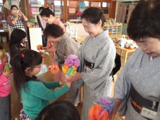 着物を着ている先生方に手作りの綺麗な花束を子ども達が手渡ししている写真