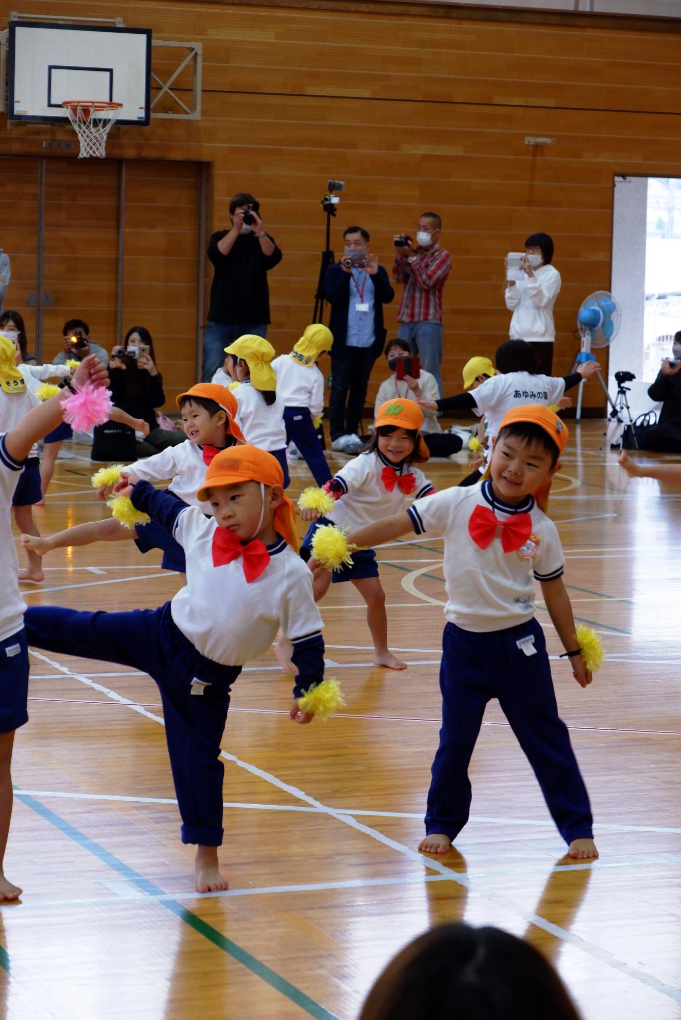 手首にポンポンを付けてダンスを踊る子ども達の写真