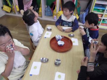 机の上にお茶とお茶菓子が置かれ、子供たちがお茶を飲んでいる写真
