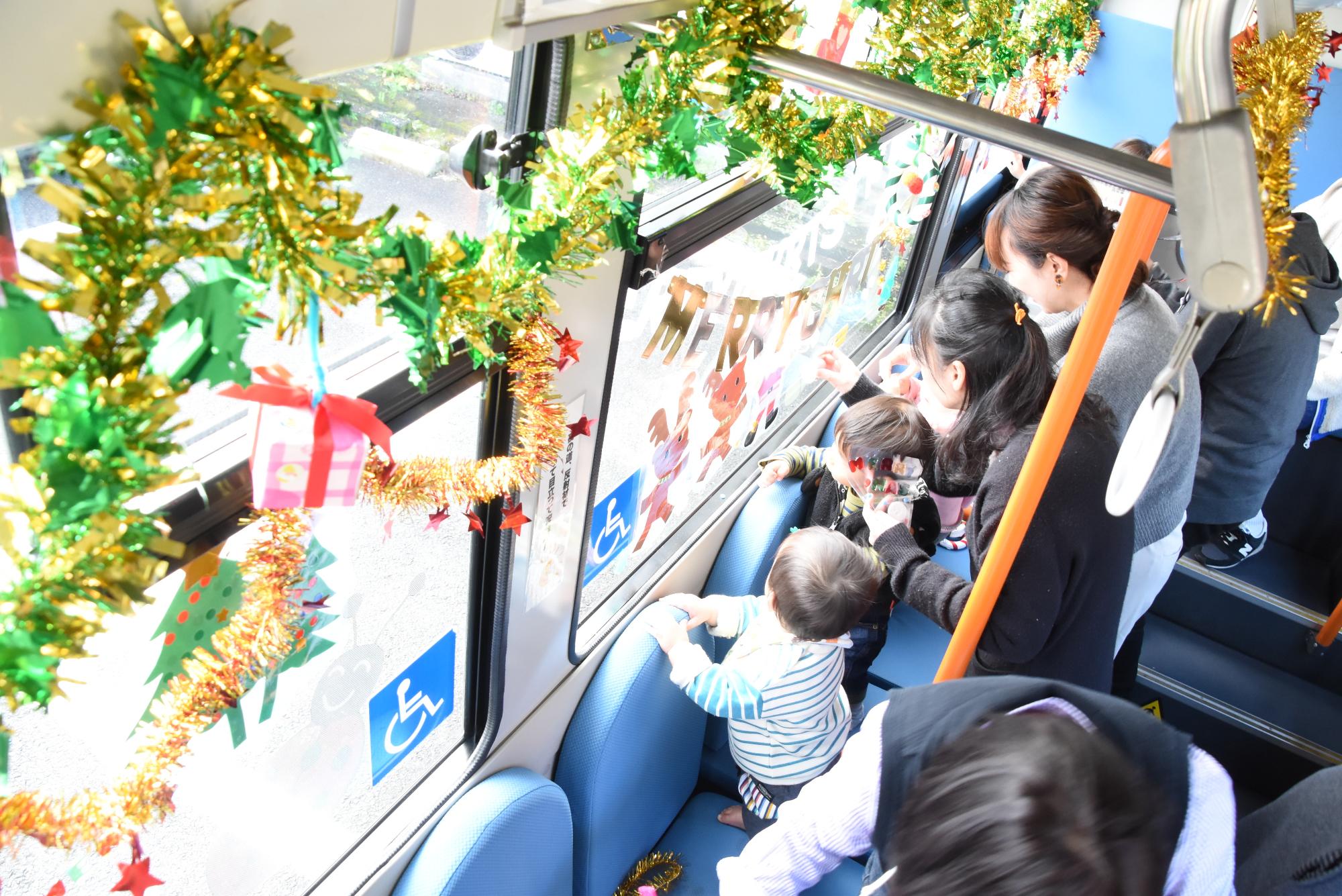町営バスに親子でシールやクリスマスリースを飾っている写真