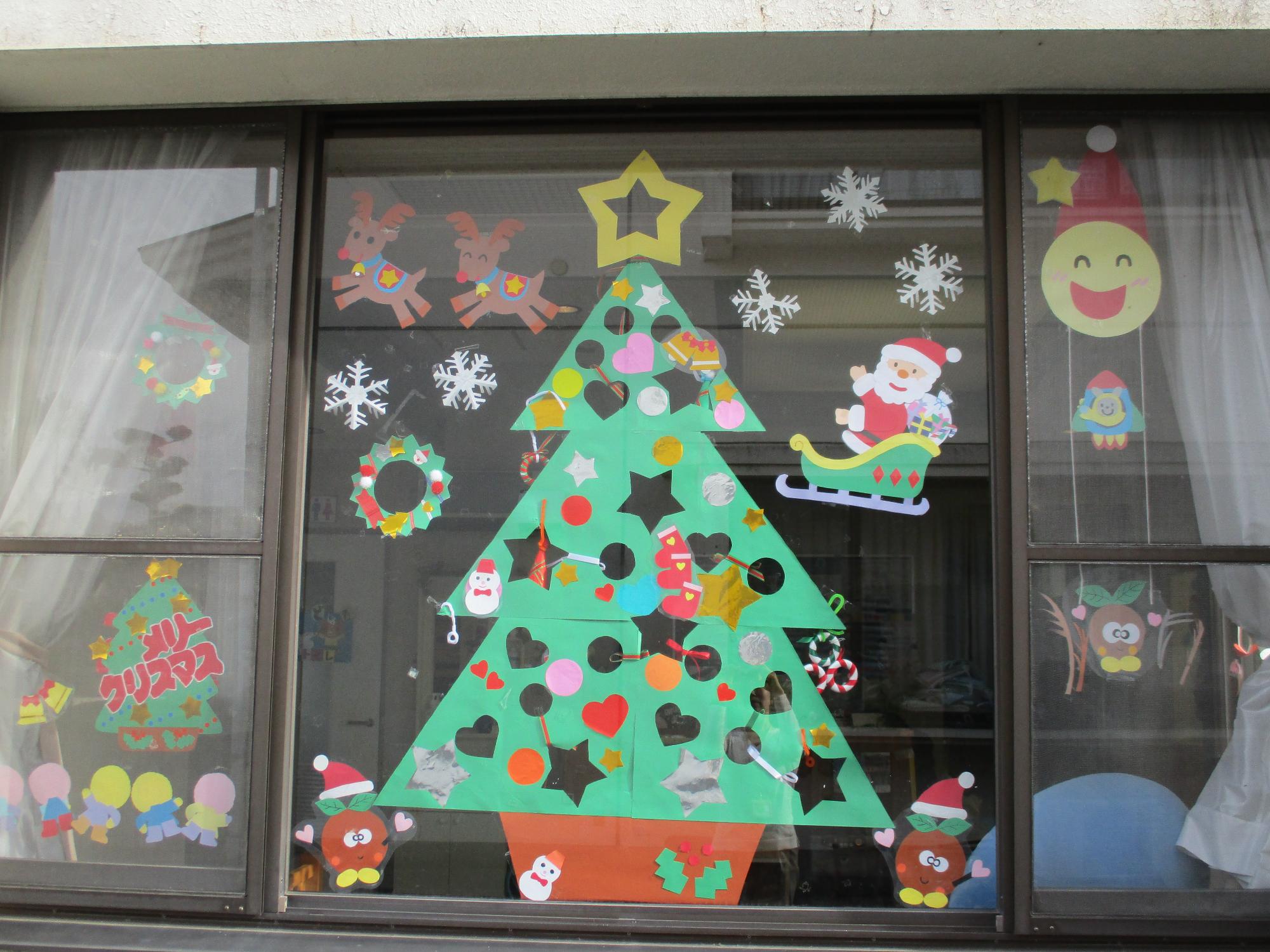 クリスマスツリーが一面に飾られた外から見た窓の写真