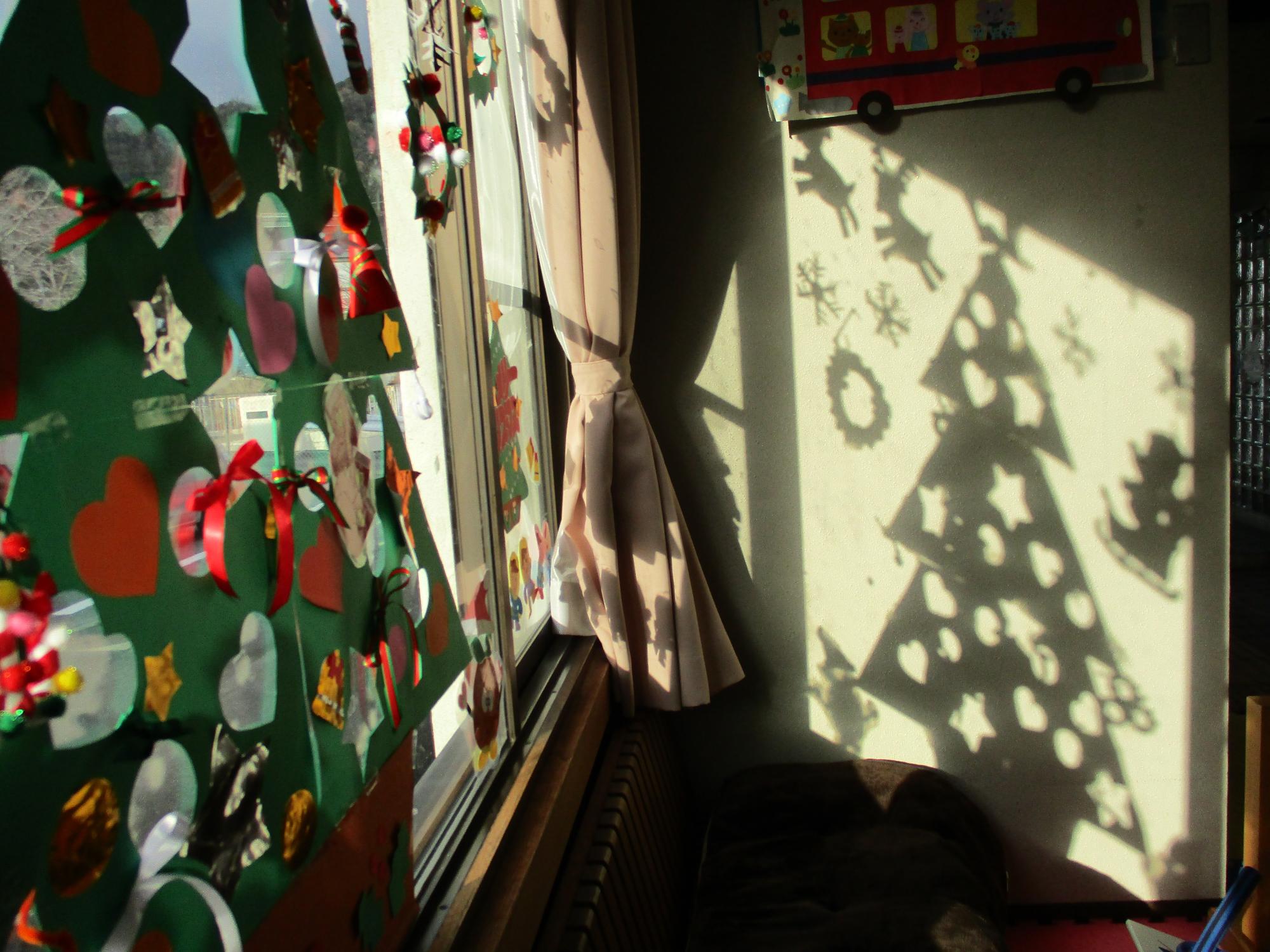 窓に当たった光でクリスマスツリーが壁に映っている写真