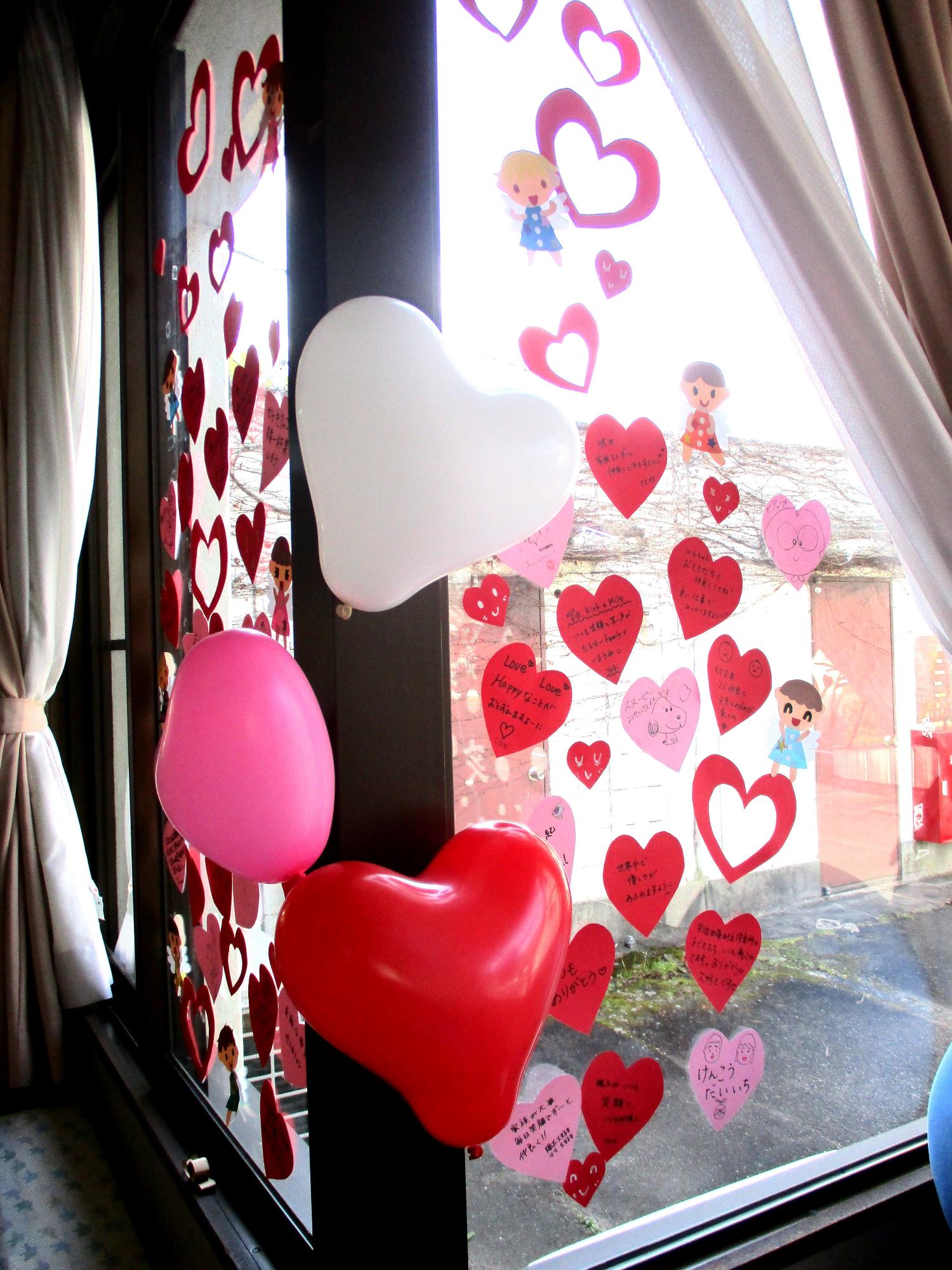 ハート型のメッセージと風船で飾られた窓の写真