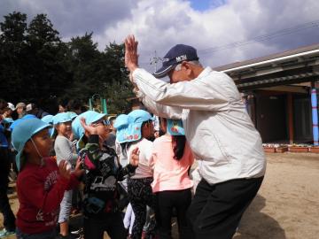 おじいさんと笑顔でハイタッチする園児らの写真