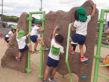 子どもたちが公園でアスレチックなどの遊具で遊んでいる様子の写真
