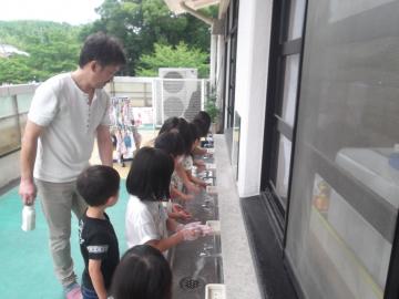 子どもたちが指導を受けながら手洗いをしている写真