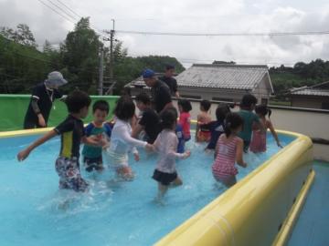 子どもたちがプールの端から端へワニ歩きで泳ぐ練習をしている様子の写真