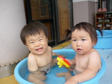子ども2人が水色のたらいに入って水遊びを楽しんでいる様子の写真