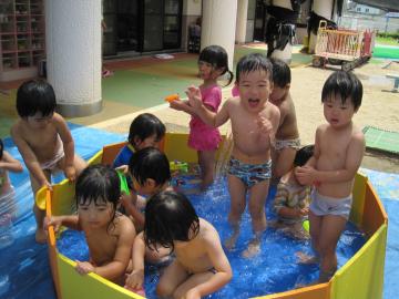 子どもたちがペットボトルの玩具や水鉄砲を使ってプールで遊んでいる様子の写真