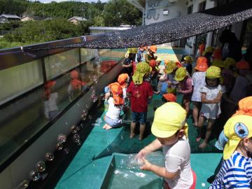 子どもたちがシャボン玉や色水で遊んでいる様子の写真