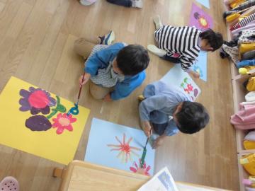 床の上で子どもたちが花の絵を描いている様子の写真