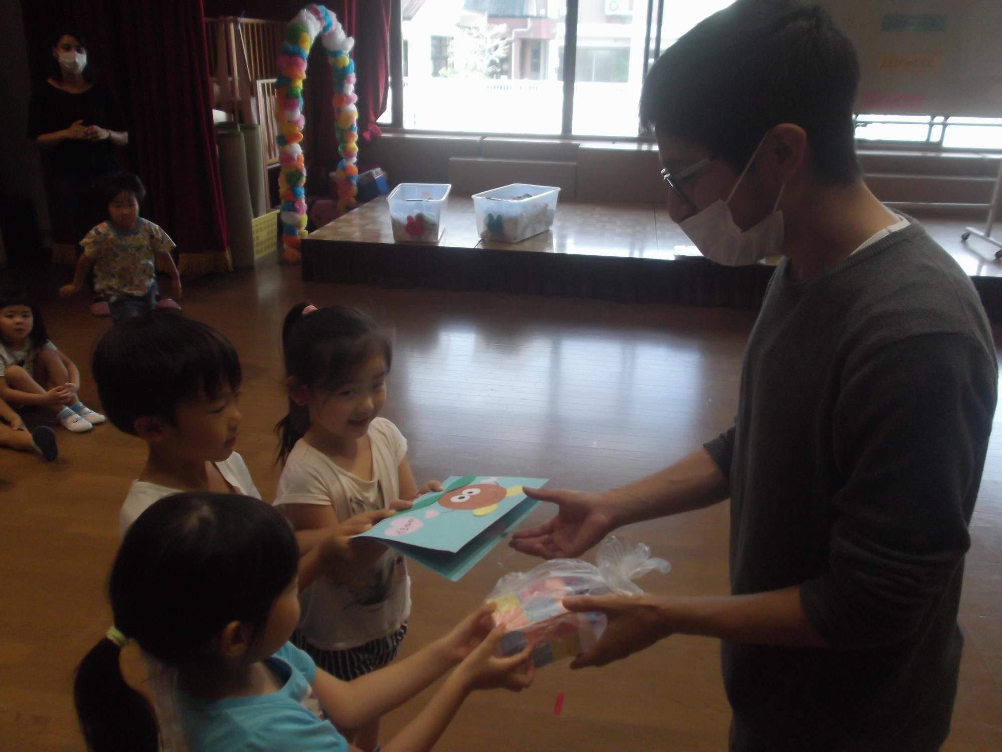 子ども達がALTの先生にプレゼントを渡している様子の写真